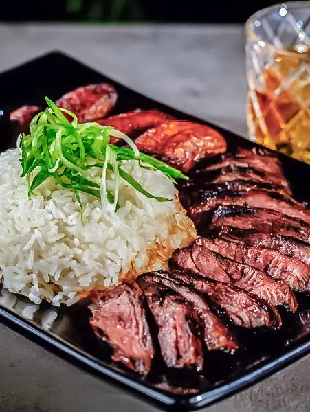 Grilled steak sliced and served with steamed white rice, topped with fresh scallions, alongside maduros and a cocktail — Casa Sensei, Fort Lauderdale
