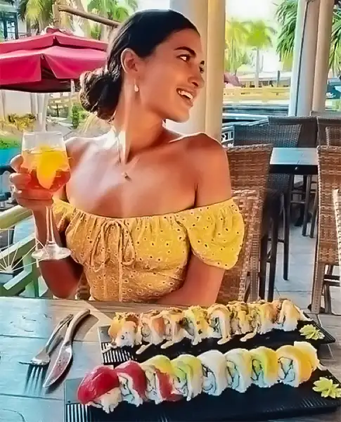 Guest enjoying a cocktail at the outdoor terrace, with a large sushi platter on the table and waterfront views in the background — Casa Sensei, Fort Lauderdale