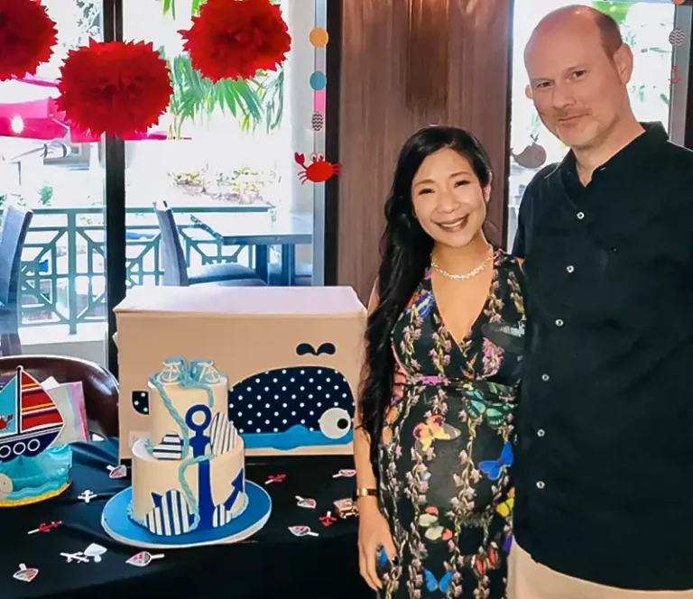 Couple celebrating a nautical-themed baby shower, with a decorated anchor and whale cake, red floral pompoms, and festive table décor — Casa Sensei, Fort Lauderdale