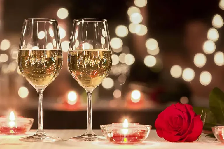 Two champagne glasses with candlelight and a red rose on a romantic dinner table — Casa Sensei, Fort Lauderdale